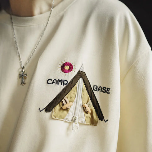 White sweatshirt with embroidered tent design and 'Camp Base' text on a plain background
